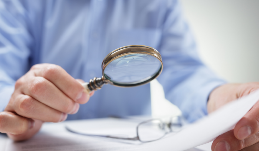 Man holding magnifying glass over paper